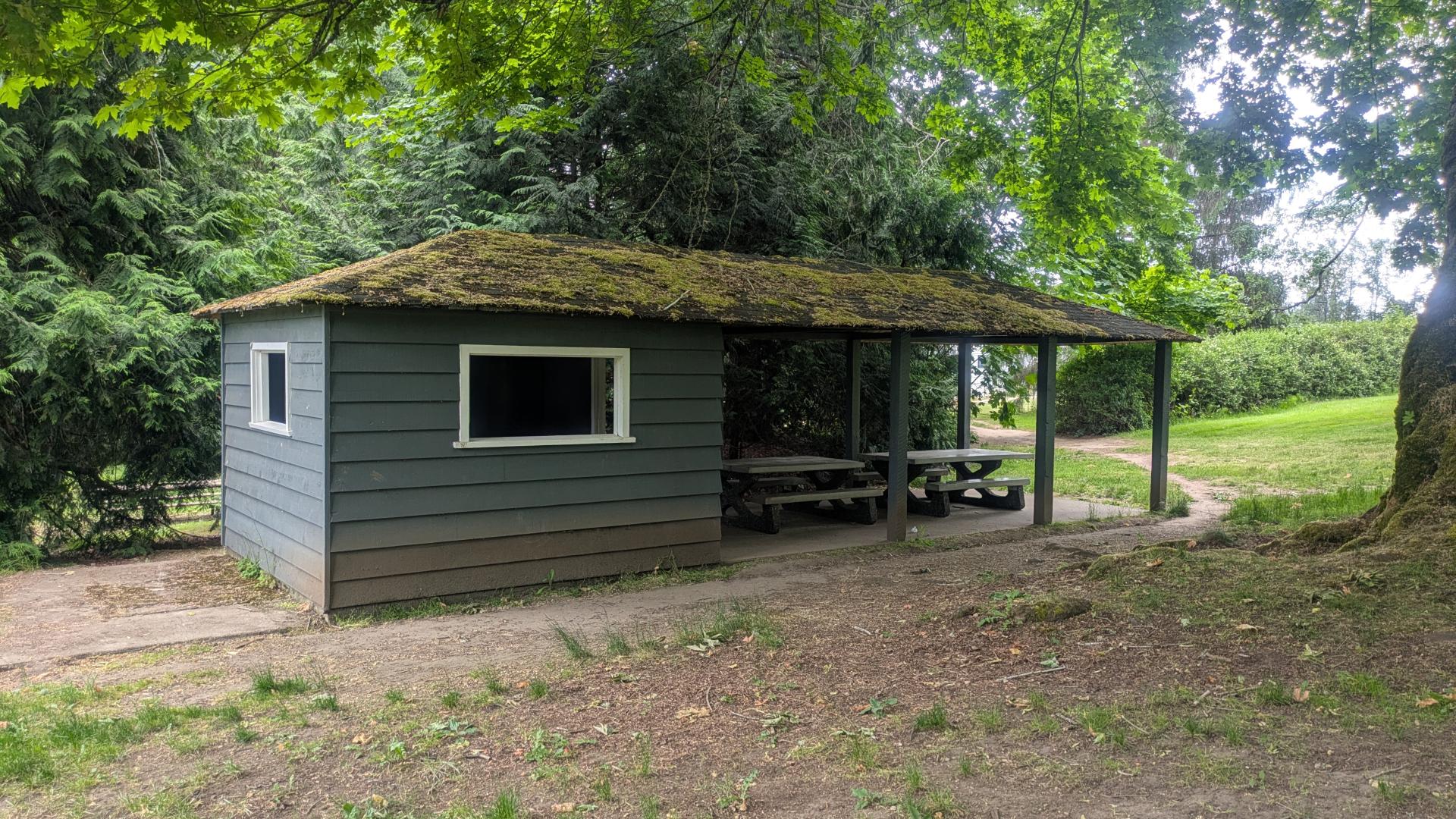 Small building with windows and a covered sitting area.