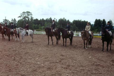 In a horse-riding corral are several horse and riders preparing for a competition.