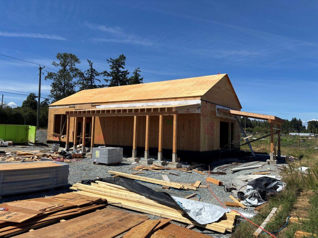 Newly constructed wooden building with a sloped roof and surrounding materials.