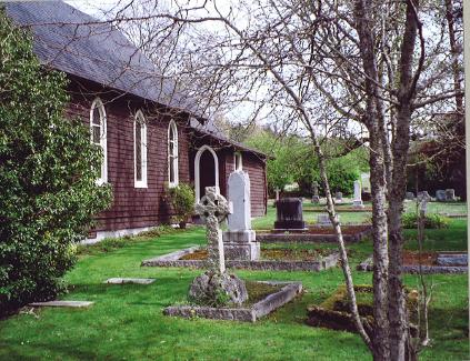 Historic church beside a tranquil cemetery with stone graves and green grass.