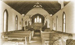 Interior of a rustic church with wooden benches and arched windows, tinted sepia.