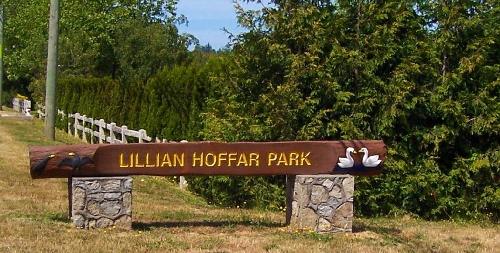 Wooden sign for Lillian Hoffar Park with decorative ducks, set in a grassy area.